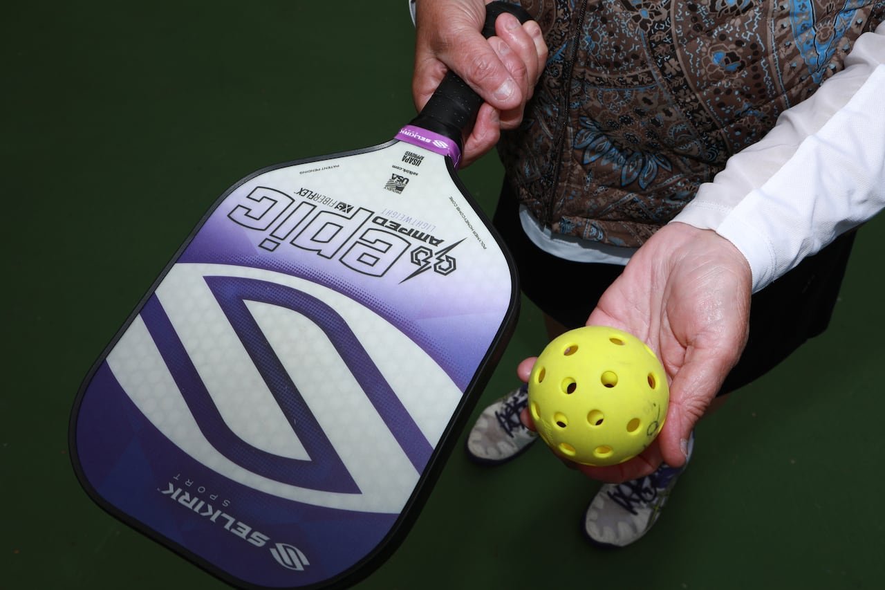 default-1743 Close up photo of a pickleball paddle and ball in a woman's hands.