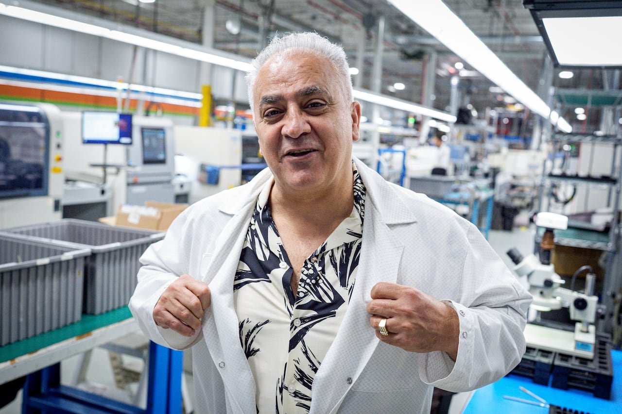 default-3236 A man putting on a white lab coat at a manufacturing plant of printed circuit boards.