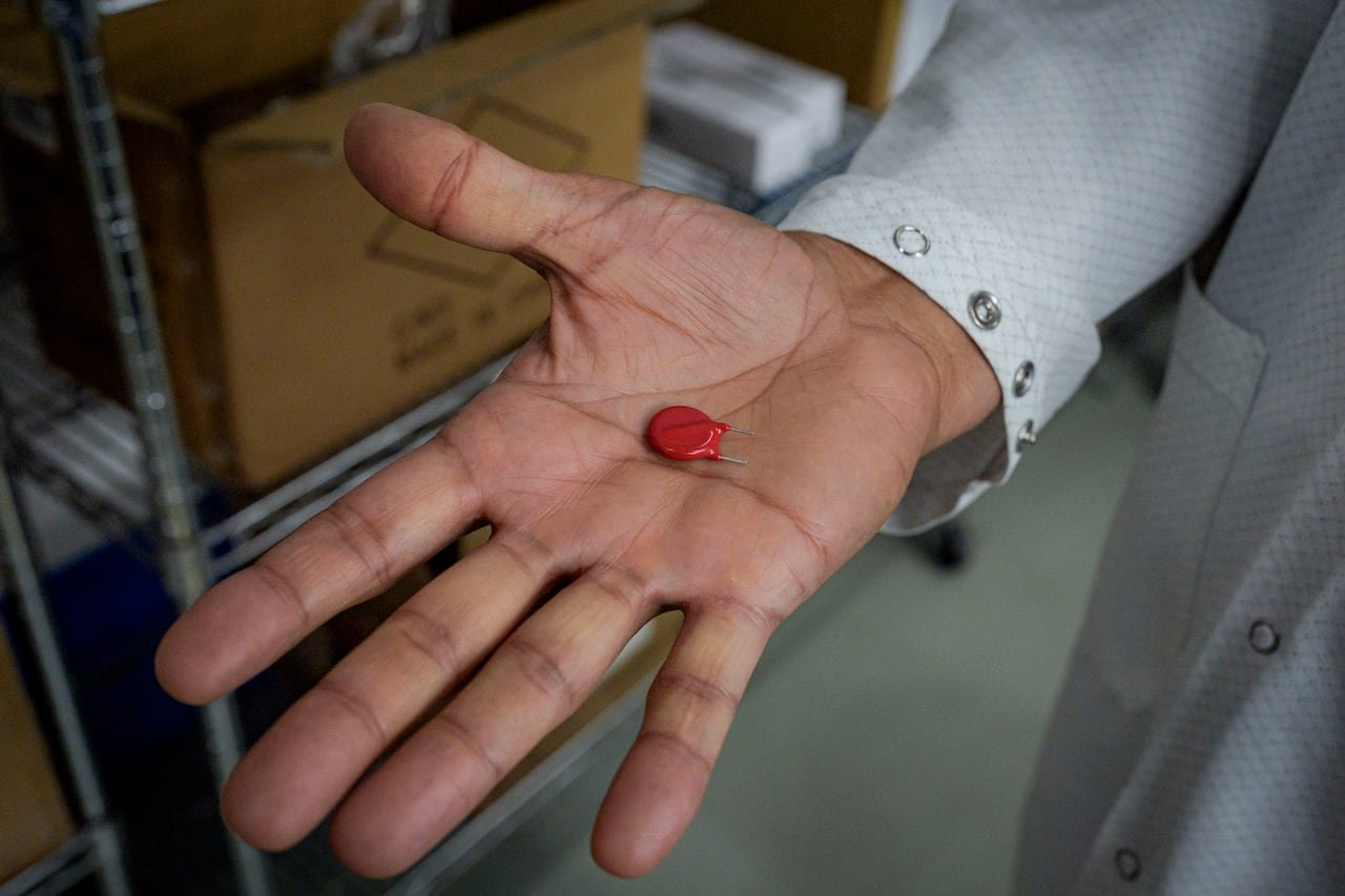 default-3237 A red component held in a person's hand.