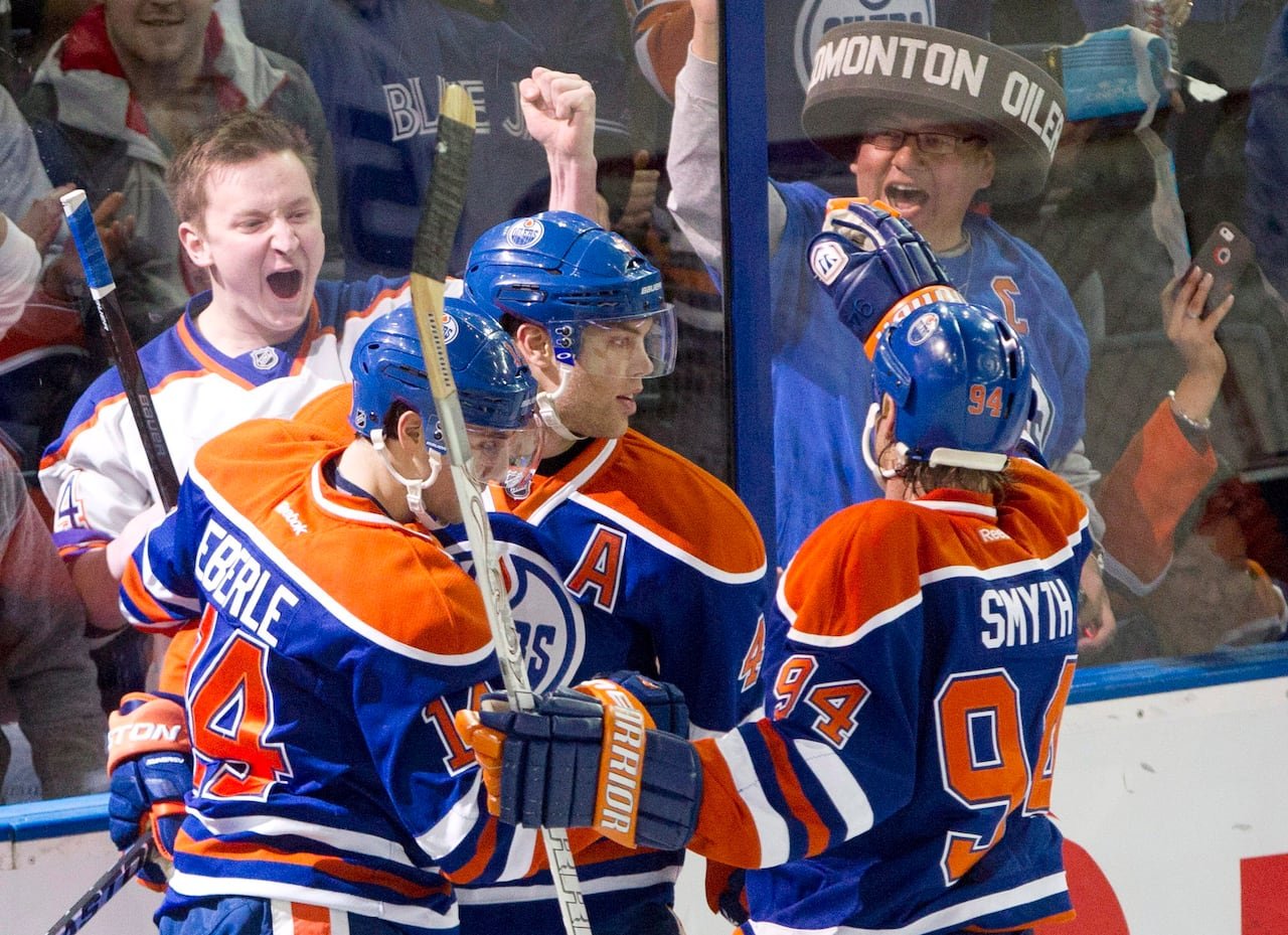 default-371 Three hockey players in orange-and-blue jerseys hug and celebrate while fans on the other side of the arena glass cheer wildly.Â