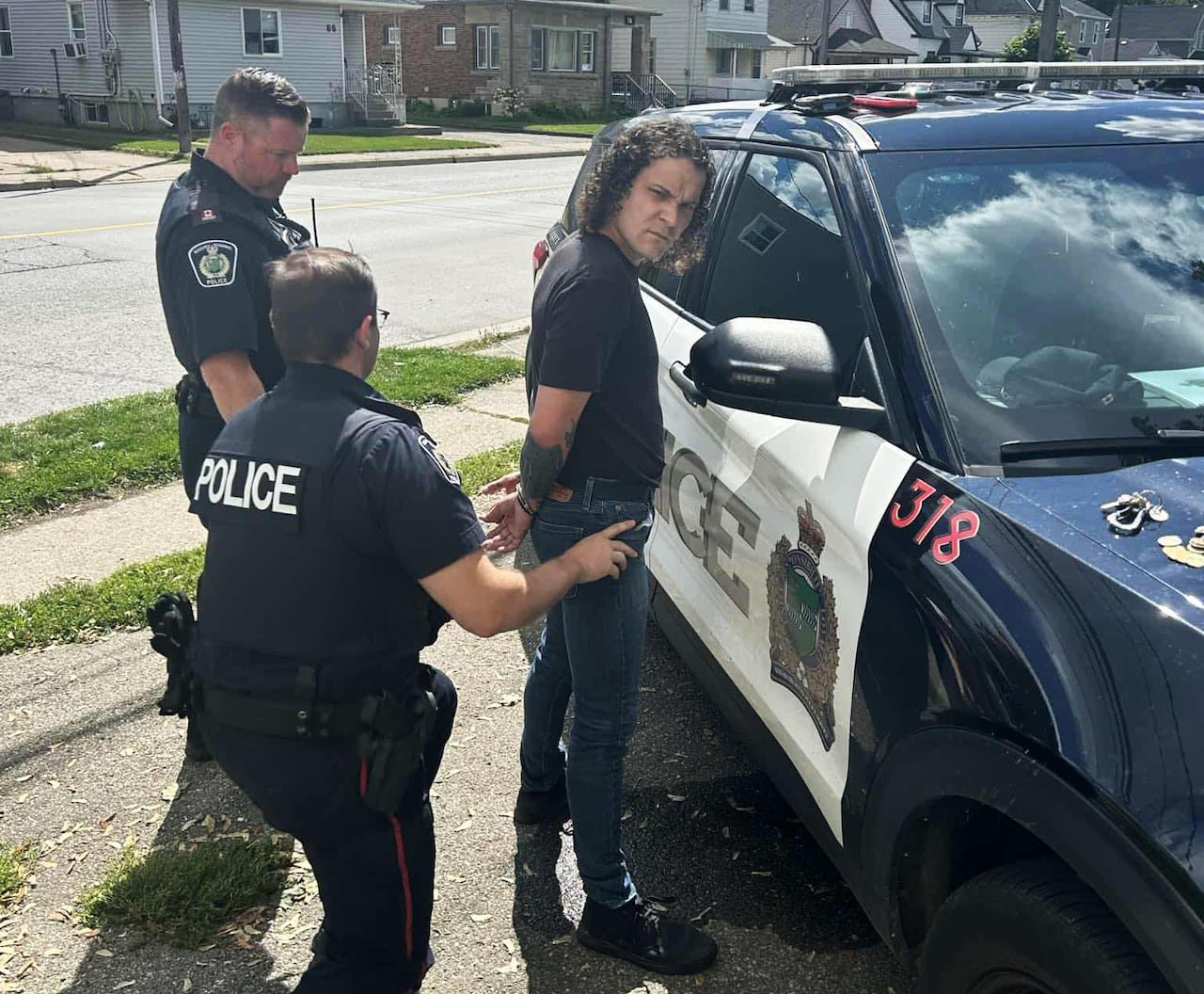 default-1396 man being handcuffed a police car with two cops behind him