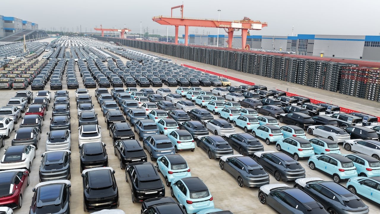 Many cars are seen from above in a large industrial lot.