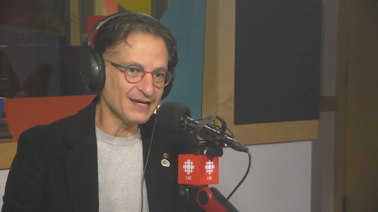 default-172 A man with rounded glasses speaks in a radio studio.