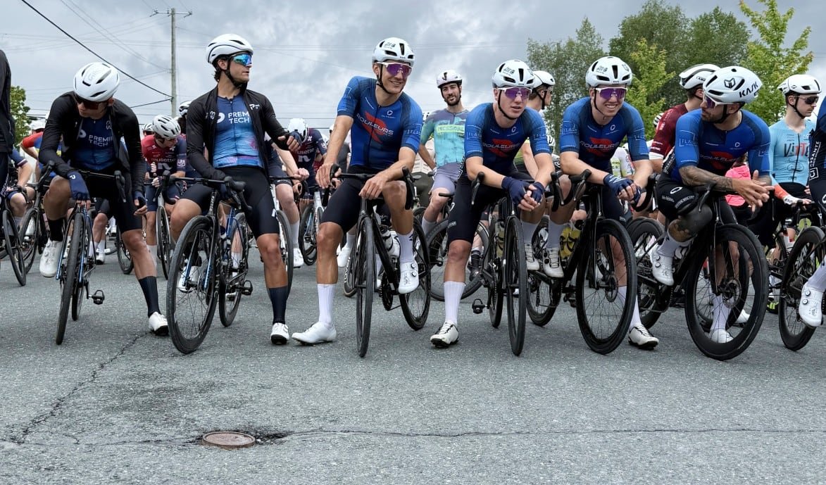 A group of men are leaning over bicycles on a road.