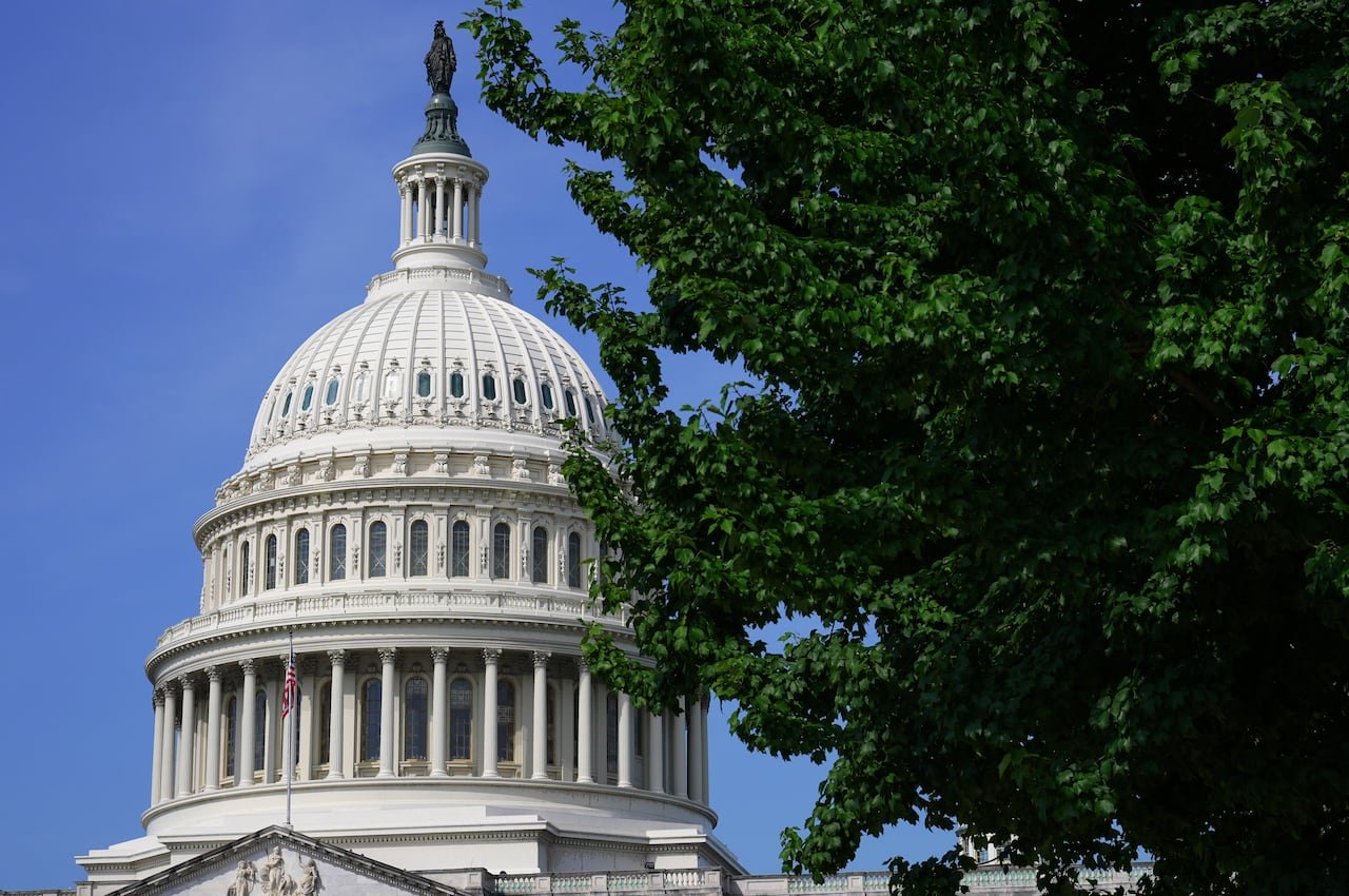 default-332 U.S. Capitol viewed against a blue sky with some trees in the foreground.