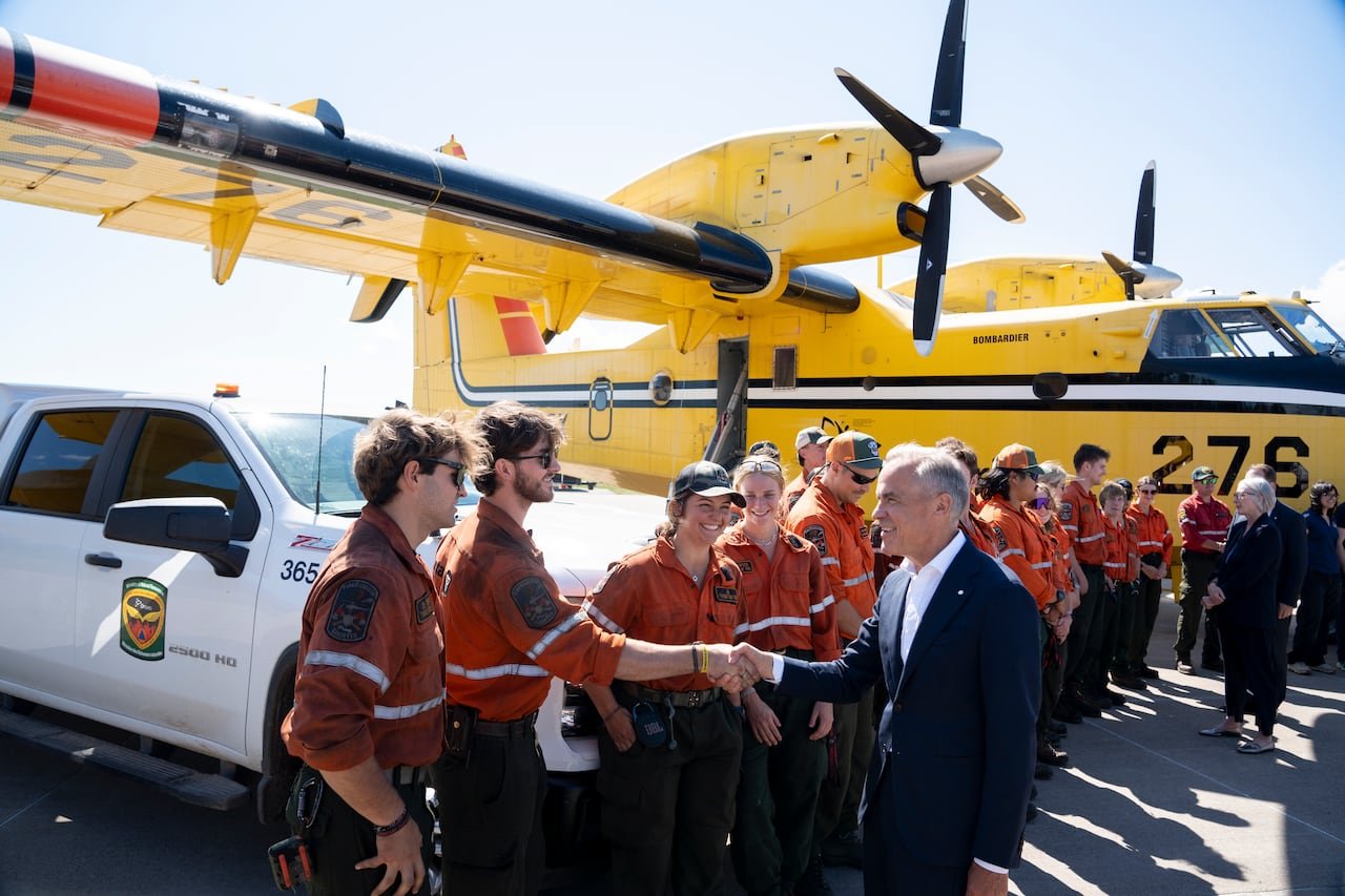 Ontario Wildland Firefighters greet Prime Minister Mark Carney in front of an airplane