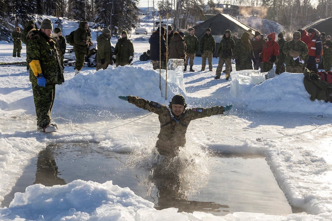 default-1215 Army reserve person jumps into ice waters with other colleagues watching outside in the cold.
