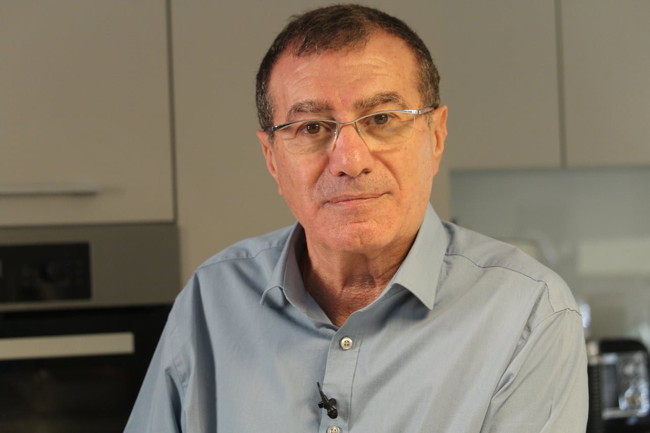 A man in a dress shirt and glasses posing for a photo.
