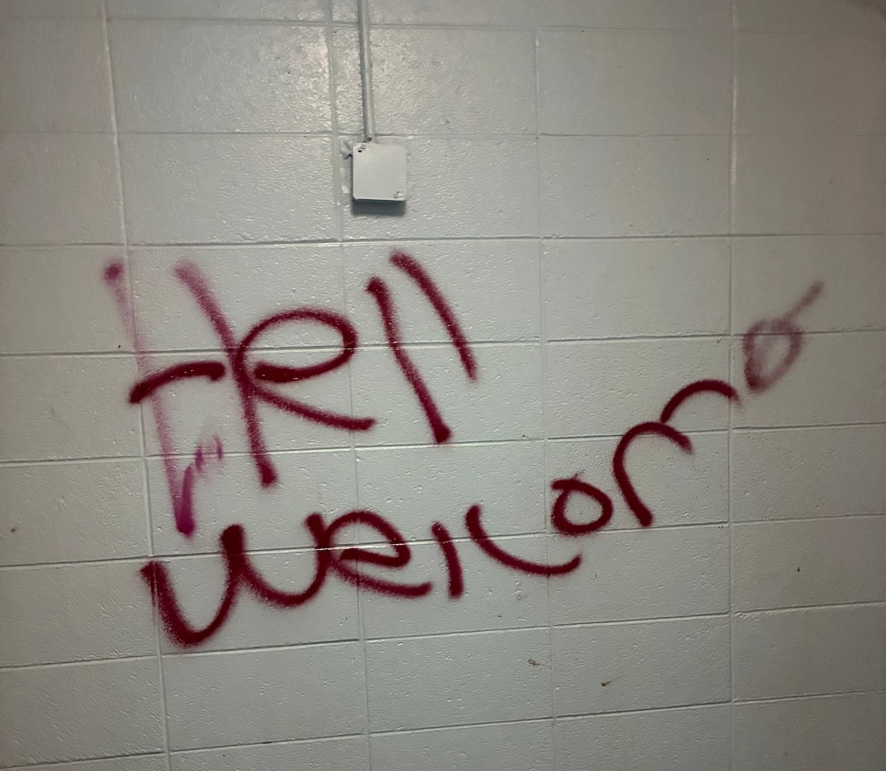 Red graffiti on a white stone wall.