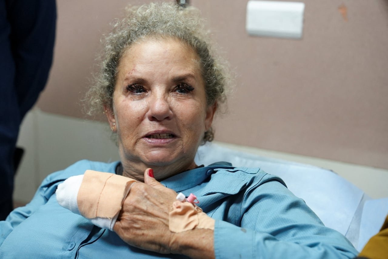 default-2480 A woman with her hand bandaged speaks in a hospital bed.