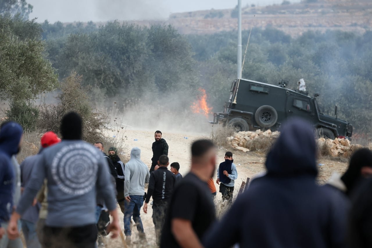 default-2481 An Israeli military vehicle is seen behind a group of Palestinians.