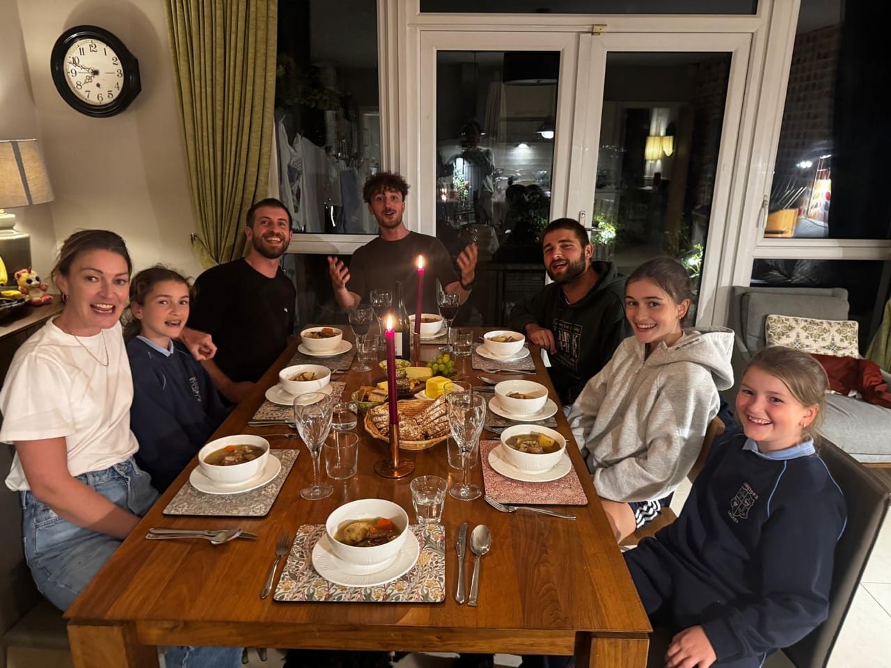 default-2612 A group of people sit around a dinner table and smile at the camera.