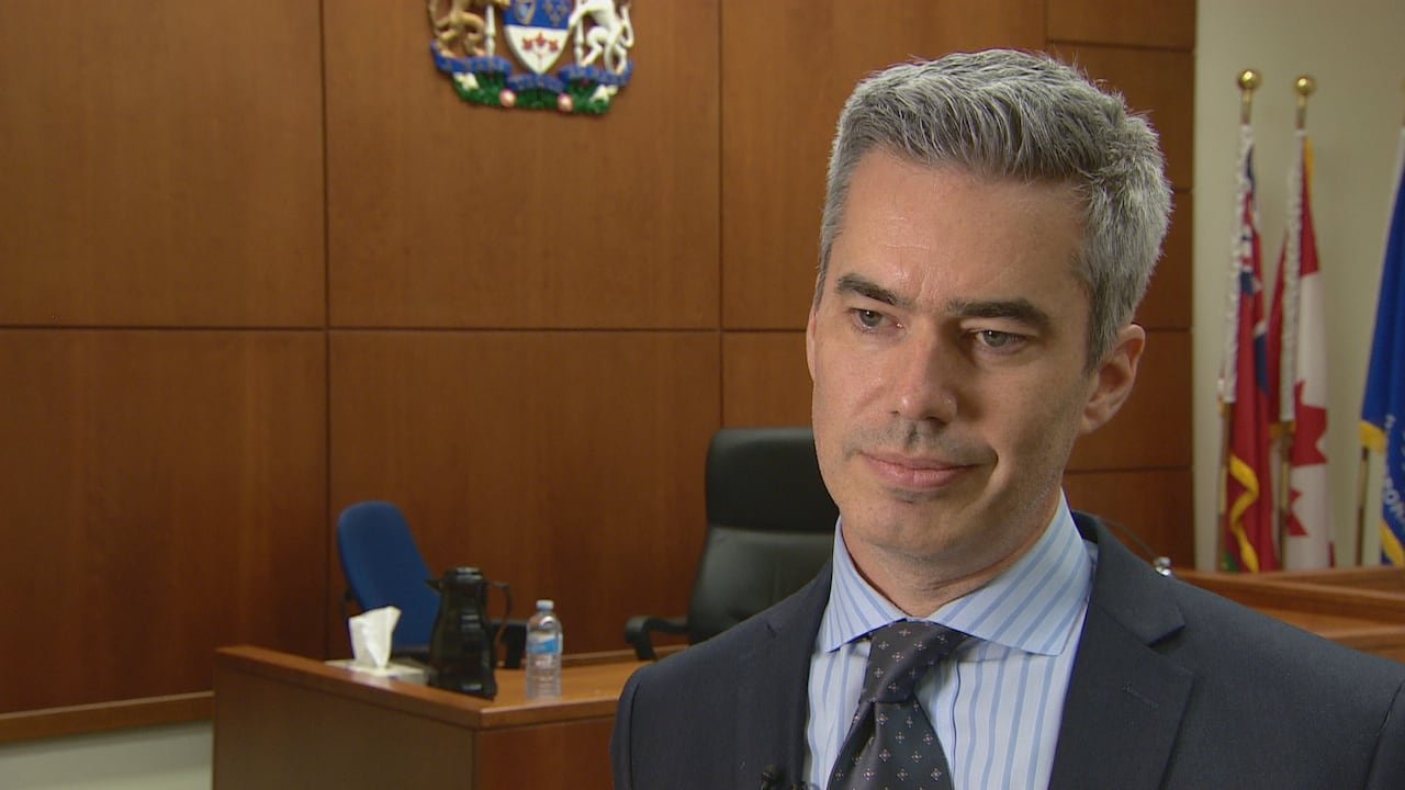 A man in a suit is interviewed in a courtroom.